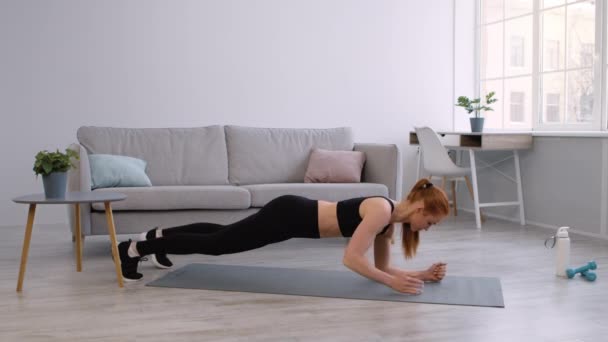 Donna che fa esercizio plancia con la transizione mano a gomito a casa — Video Stock