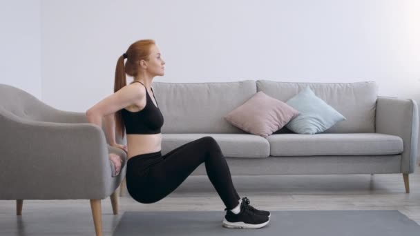 Fitness Mujer haciendo sentadillas haciendo ejercicio cerca de la silla de brazo en casa — Vídeos de Stock