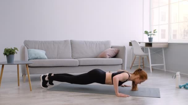 Deportiva mujer haciendo push ups haciendo ejercicio en el suelo en casa — Vídeo de stock