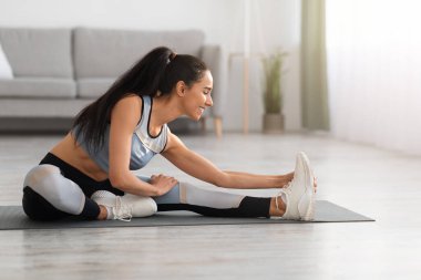 Neşeli sporcu kadın evde egzersiz yapıyor.