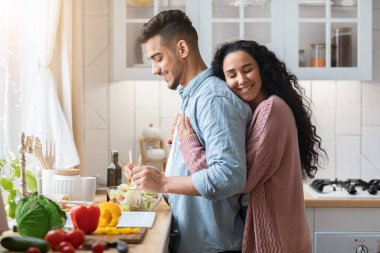 Mutfakta yemek pişirirken kocasını kucaklayan Arap Kadınını Sevmek
