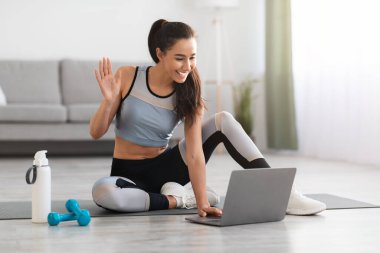 Güzel bir bayan spor hocasıyla çevrimiçi konferans yapıyor, laptop kullanıyor.