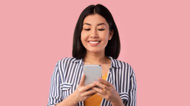 Stüdyoda cep telefonu kullanan mutlu Asyalı genç kadın.