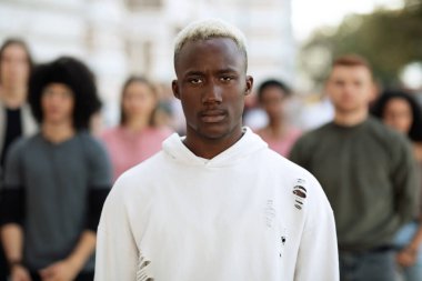 Bir grup gencin başında dikilen siyah adamın portresi.