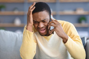 Üzgün siyahi adamın telefonda konuştuğu yakın plan.