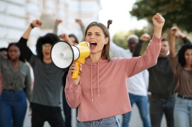 Protestoculardan oluşan megafonlu genç bir kadın.