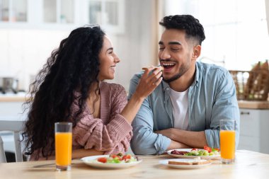 Kahvaltı vakti geldi. Neşeli Arap çift, mutfakta sabah yemeği yiyor.