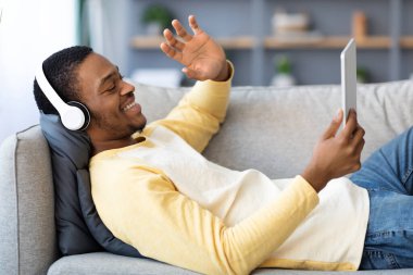 Siyah adam dijital tablet kullanarak arkadaşlarıyla görüntülü konuşma yapıyor.