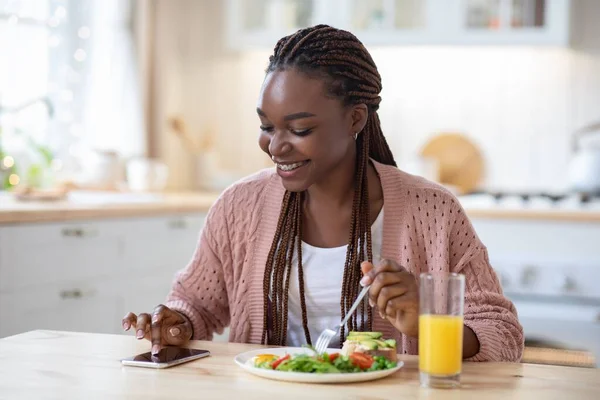 Callories Counting App. Mujer negra usando smartphone mientras desayuna en la cocina — Foto de Stock