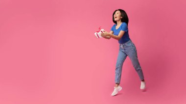 Heyecanlı Asyalı kadın hediye kutusunu tutuyor.