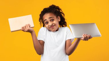 Belirsiz siyah kız elinde kitap ve tabletle stüdyoda duruyor.