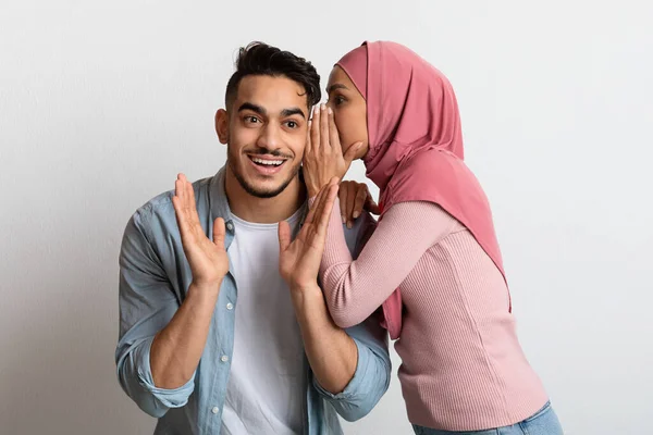 コンセプトはゴシップ。彼女の驚きのボーイフレンドに秘密をささやくヒジャブのイスラム教徒の女性 — ストック写真
