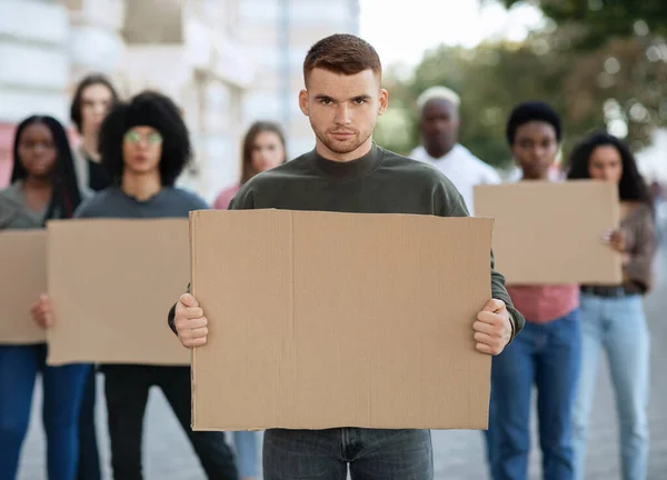 Confident guy leading a group of demonstrators with placards