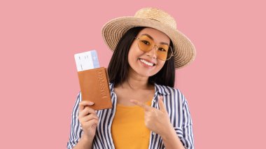 Asyalı kadın elinde biletlerle pasaportunu işaret ediyor.