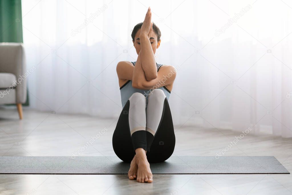Flexible woman sitting on fitness mat, enjoying yoga practice