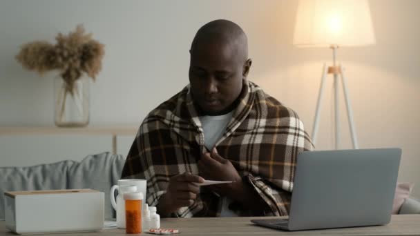 Chory czarny człowiek mając gorączka gospodarstwa termometr siedzi w domu — Wideo stockowe