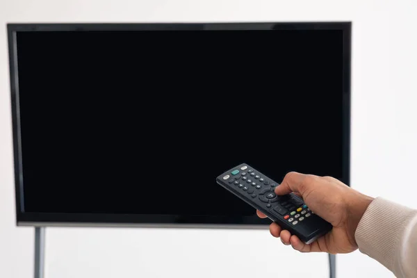Black man watching TV and using remote controller