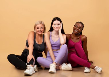 Üç farklı gülümseyen etnik kadın portresi spor kıyafetlerinde poz veriyor.