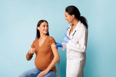 Hamile Kadın ve Hemşire, Aşıyı Onaylayan Başparmak Hareketi, Mavi Arkaplan