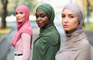 Üç farklı milenyum bayanı açık havada poz veriyor.