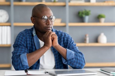 İş planını düşünüyorum. Düşünceli siyahi girişimci yurtiçi ofiste yeni bir proje üzerinde çalışıyor.