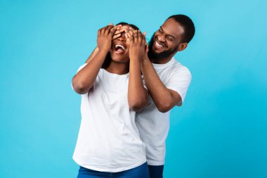 Mutlu siyah adam, karısına sürpriz yapıyor, gözlerini kapatıyor.