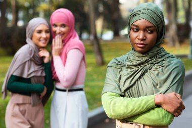 Açık havada siyah Müslüman Kadın 'ın Arkasına Fısıldayan Arap Kadınları