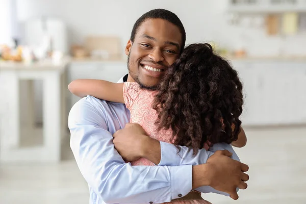 Happy black dad hugging his cute little daughter