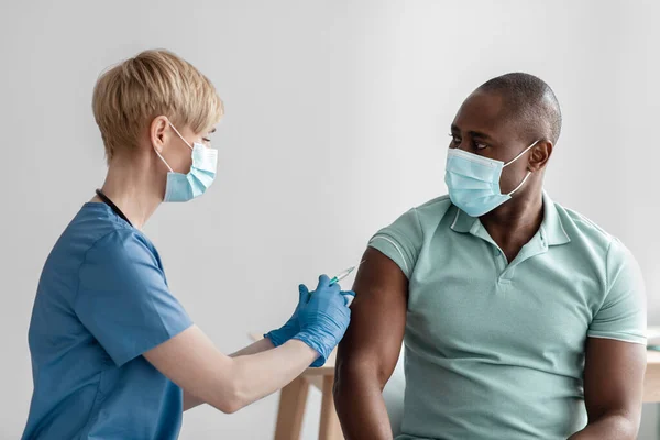 Vaccination, immunization, disease prevention, man in medical mask getting Covid-19 or flu vaccine