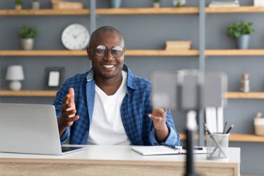 Teknoloji blogcusu. Olgun siyahi adam internet günlüğü için video içeriği kaydediyor, kameraya işaret ediyor.