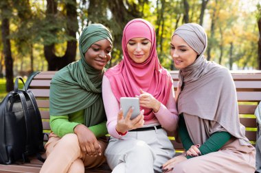 Müslüman Öğrenciler Açık havada Oturan Eğitimsel Uygulamalı Akıllı Telefon Kullanıyor
