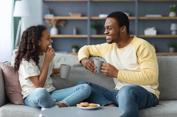 Söt svart far och dotter dricker te med kakor — Stockfoto