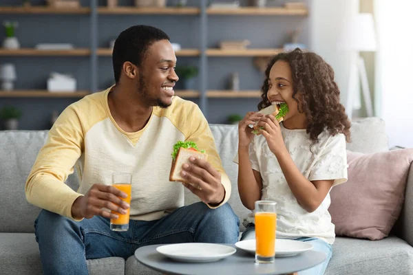 Beautiful black family father and daughter having snack at home