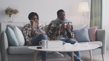 Genç Afro-Amerikalı hasta çift evde tek başına oturuyor, ateşi ve burnu akıyor.