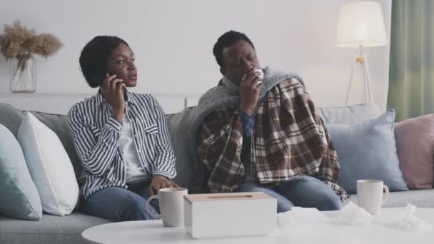 Prendersi cura della donna afroamericana che chiama il medico, toccare la fronte del marito malato, seduto sul pullman a casa — Video Stock