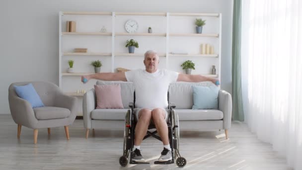 Zdravotně postižený starší muž v invalidním vozíku cvičení s činkami doma — Stock video