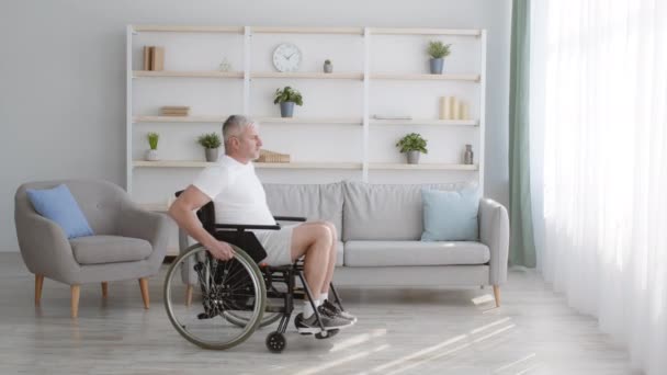 Gehandicapte oudere man in een rolstoel rijdt ongeldig vervoer thuis — Stockvideo