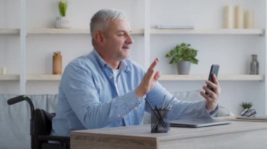 Tekerlekli sandalyede oturan akıllı telefonu kullanan engelli adam videosu.