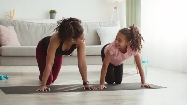 幸せなアフリカ系アメリカ人の母親と娘が自宅で運動し、ストレートアームで板を練習し、スローモーション — ストック動画