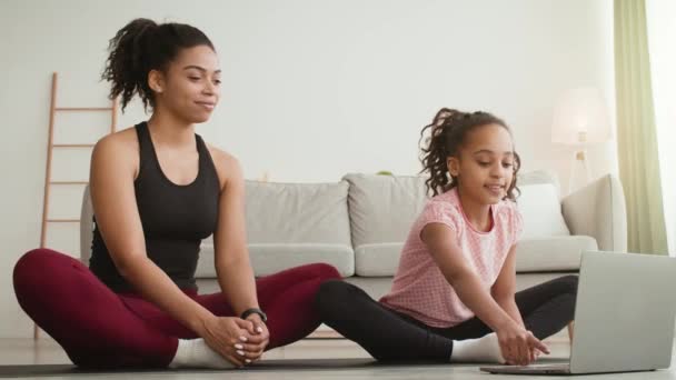Mãe americana africana feliz e filha praticando ioga on-line, tutor de saudação via chamada de vídeo no laptop — Vídeo de Stock