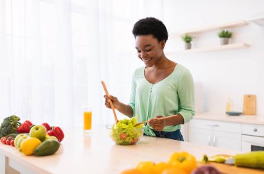 Akşam yemeği için salata yapan Afrikalı kadın. Ev yemeğinin tadını çıkarıyor.