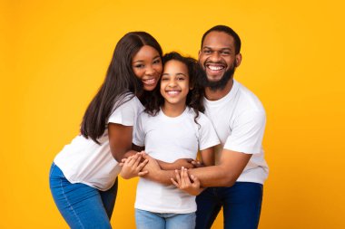 Afrikalı erkek ve kadın gülümseyen kıza sarılıyorlar.