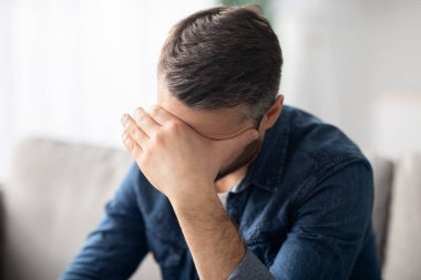 Başı ağrıyan, alnına dokunan üzgün adam.