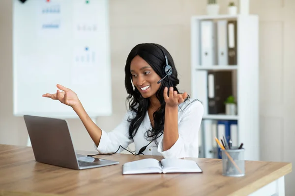 Smiling entrepreneur or office worker in headset speaking with business partner, having online videocall in office