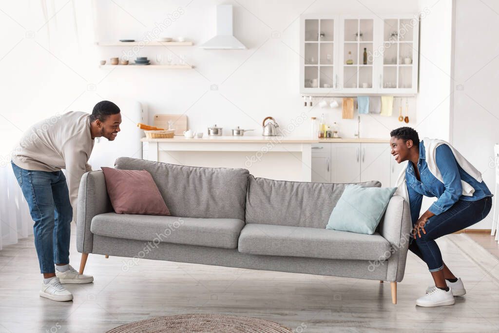 Happy black couplereplacing furniture in their new apartment
