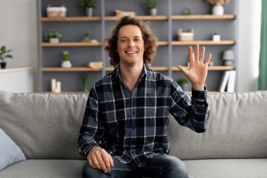 Evdeki koltukta el sallayan neşeli adam.