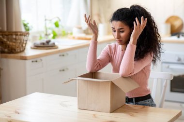 Yanlış paket. Mutfakta paketsiz bir şekilde oturan üzgün kadın.