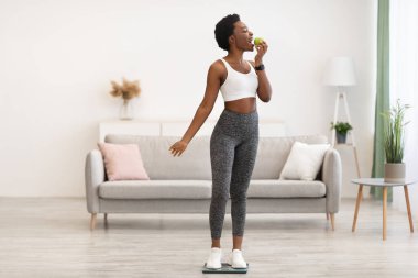 Siyah Kadın Elma Yiyor Terazinin üzerinde Durarak Ağırlığını Evde Veriyor