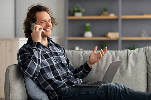 Freelancer Guy Talking On Phone Sitting With Laptop At Home
