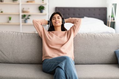 Müzik dinleyen, kulaklık takan genç bir kadın.